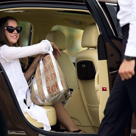 Luxury taxi service, chauffeur opening car door for female passenger, travel Luxury taxi service